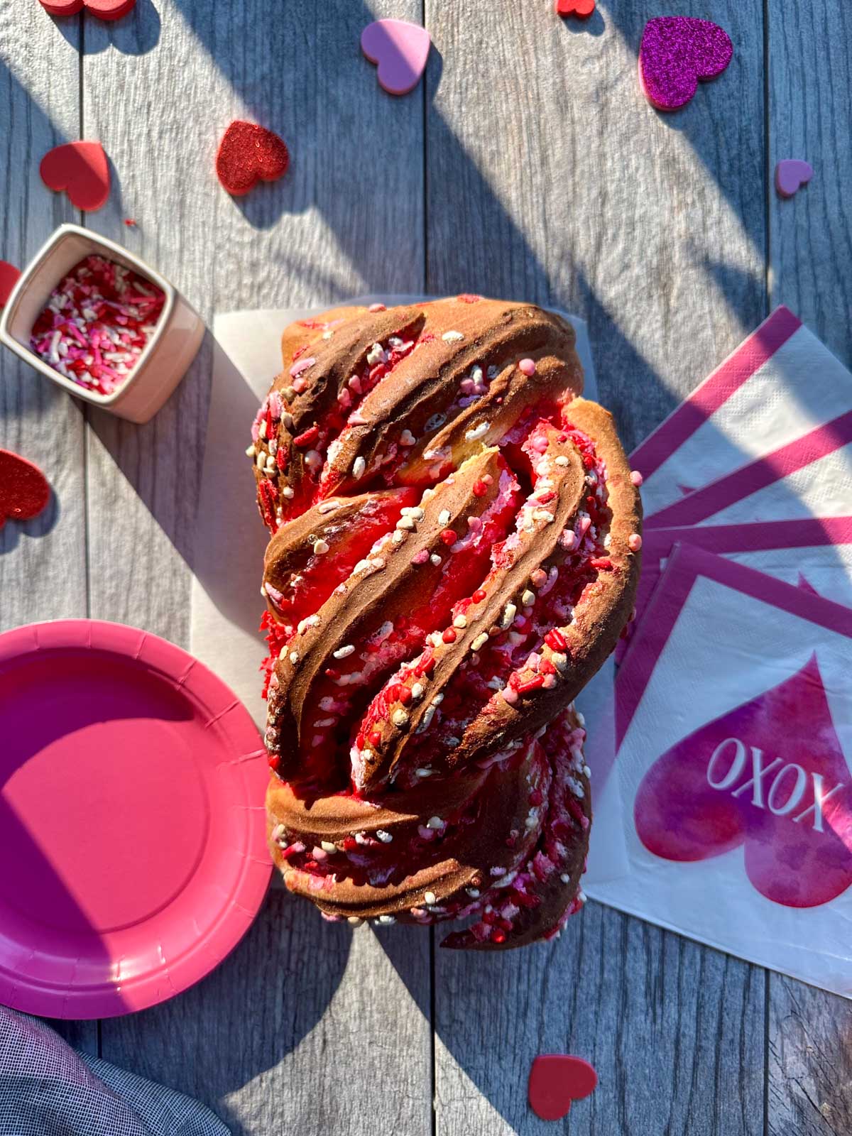 Valentines Babka with pink plates, and heart napkins, sprinkles, and the babka has sprinkles in it too.