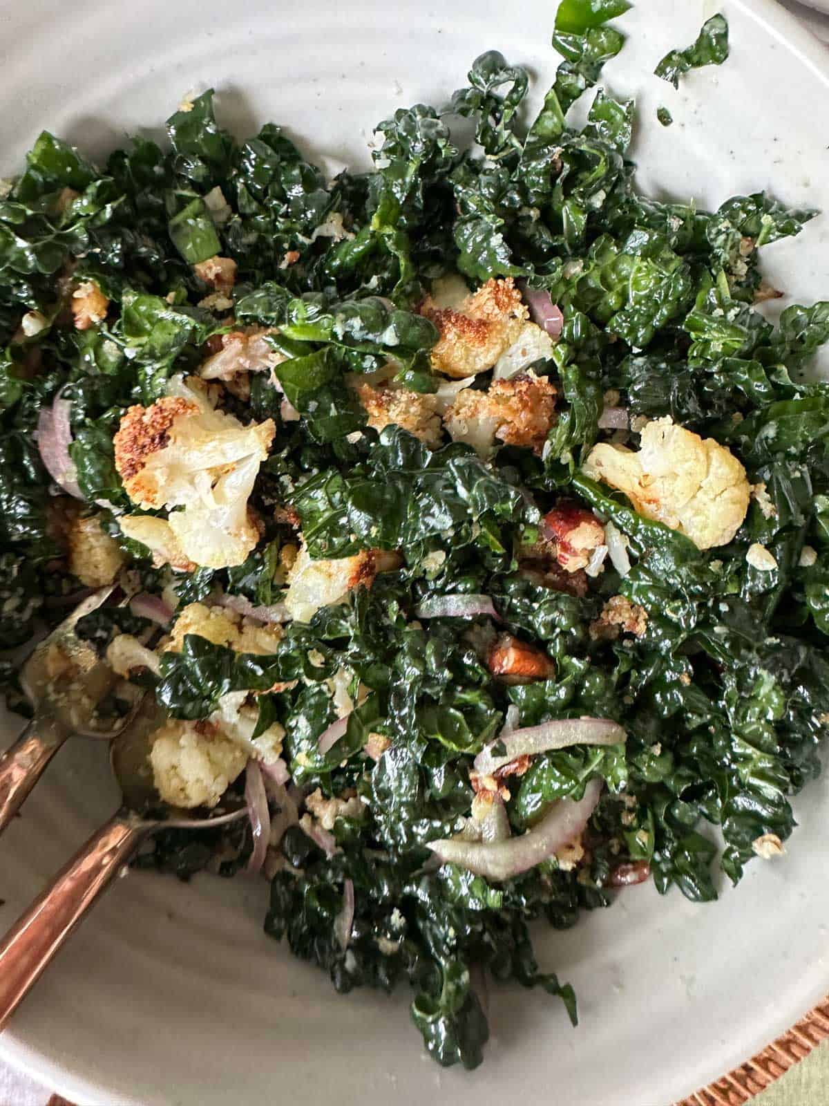 Close-up shot of Crispy Cauliflower & Kale Salad in a bowl with a fork and spoon.