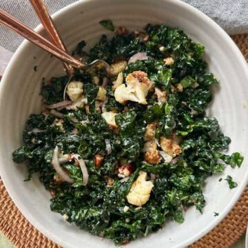 Crispy Cauliflower & Kale Salad in a bowl with a fork and spoon.