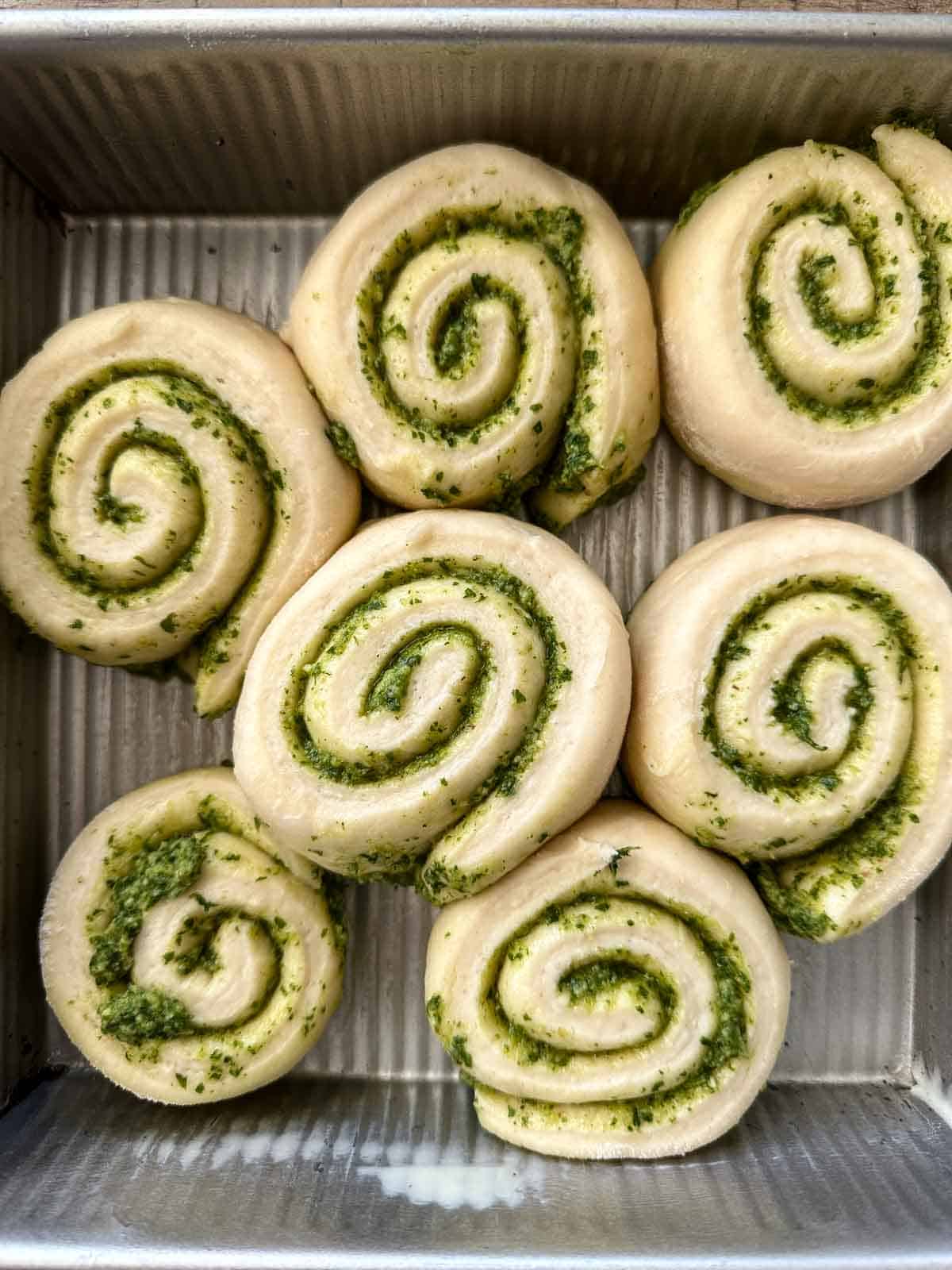 Unbaked Pesto Pinwheel Pull apart bread in a baking dish.