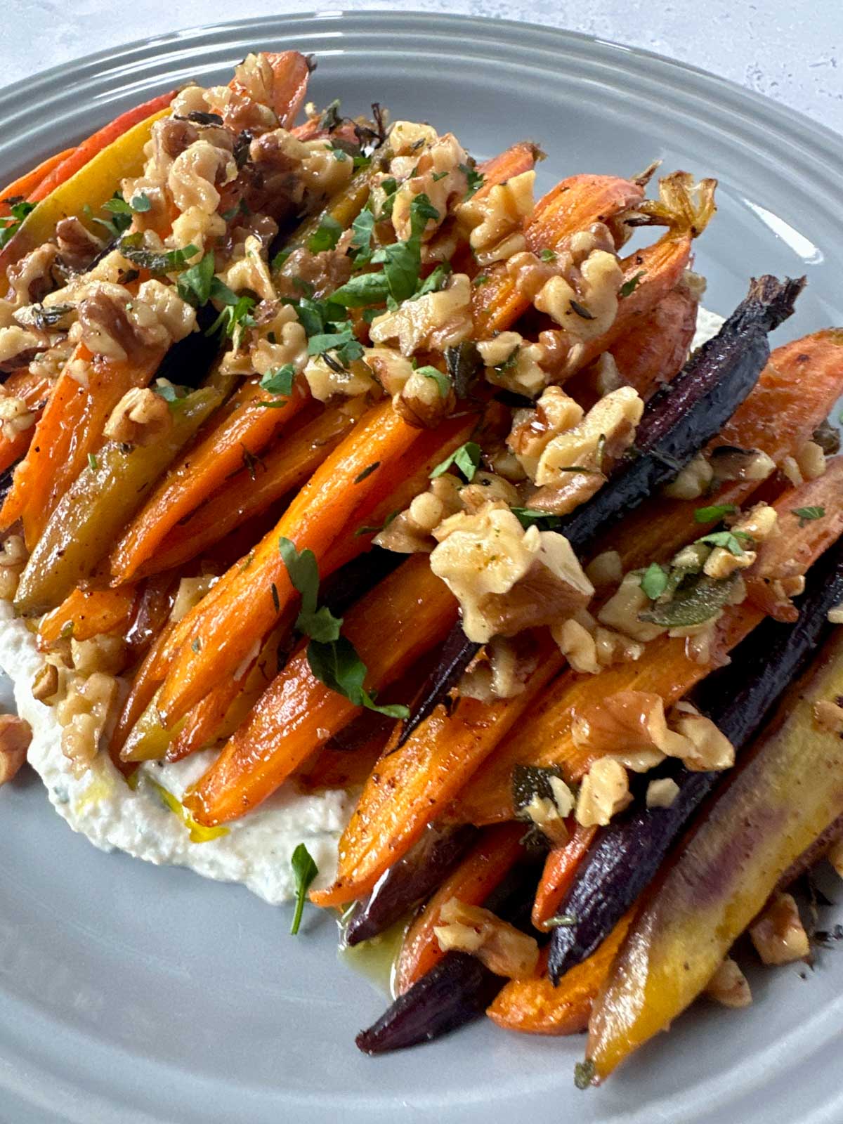 Brown Butter Roasted Carrots with Sage, topped with walnuts and garnished with parsley.