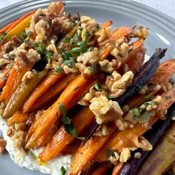 Brown Butter Roasted Carrots with Sage topped with walnuts and garnished with parsley.