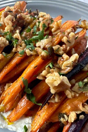 Brown Butter Roasted Carrots with Sage topped with walnuts and garnished with parsley.